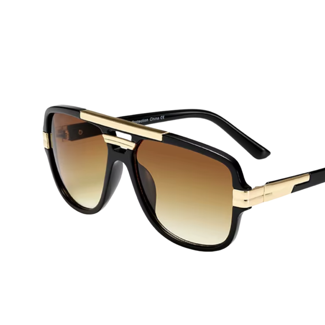 Aviator-style sunglasses with a black frame, gold metal bridge and temple accents, and brown gradient lenses, shown on a plain white background.